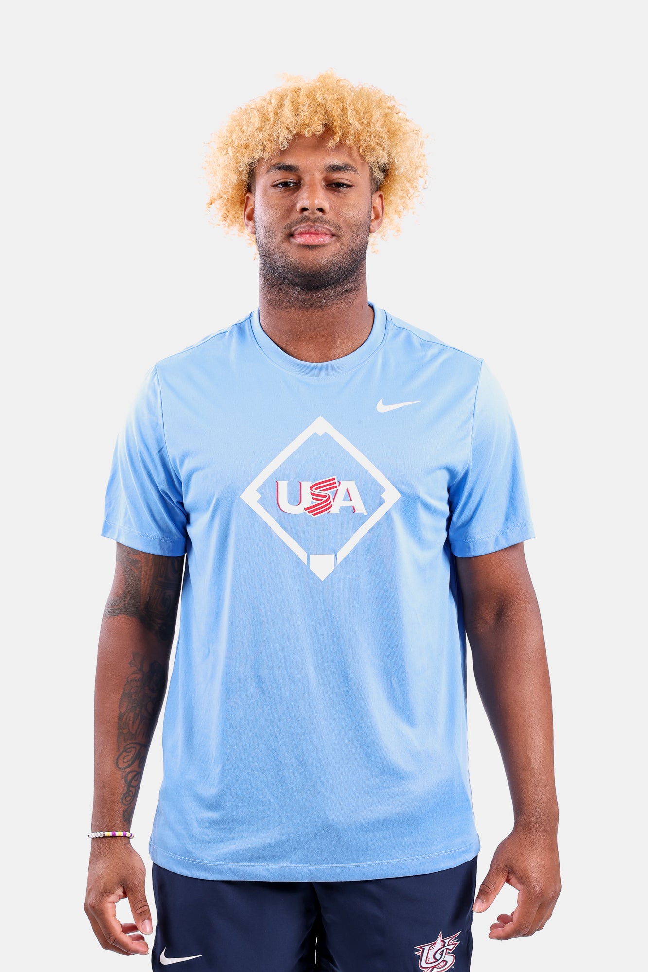 Male model wearing the Light Blue Home Plate Legend Tee featuring the USA Baseball Jersey logo