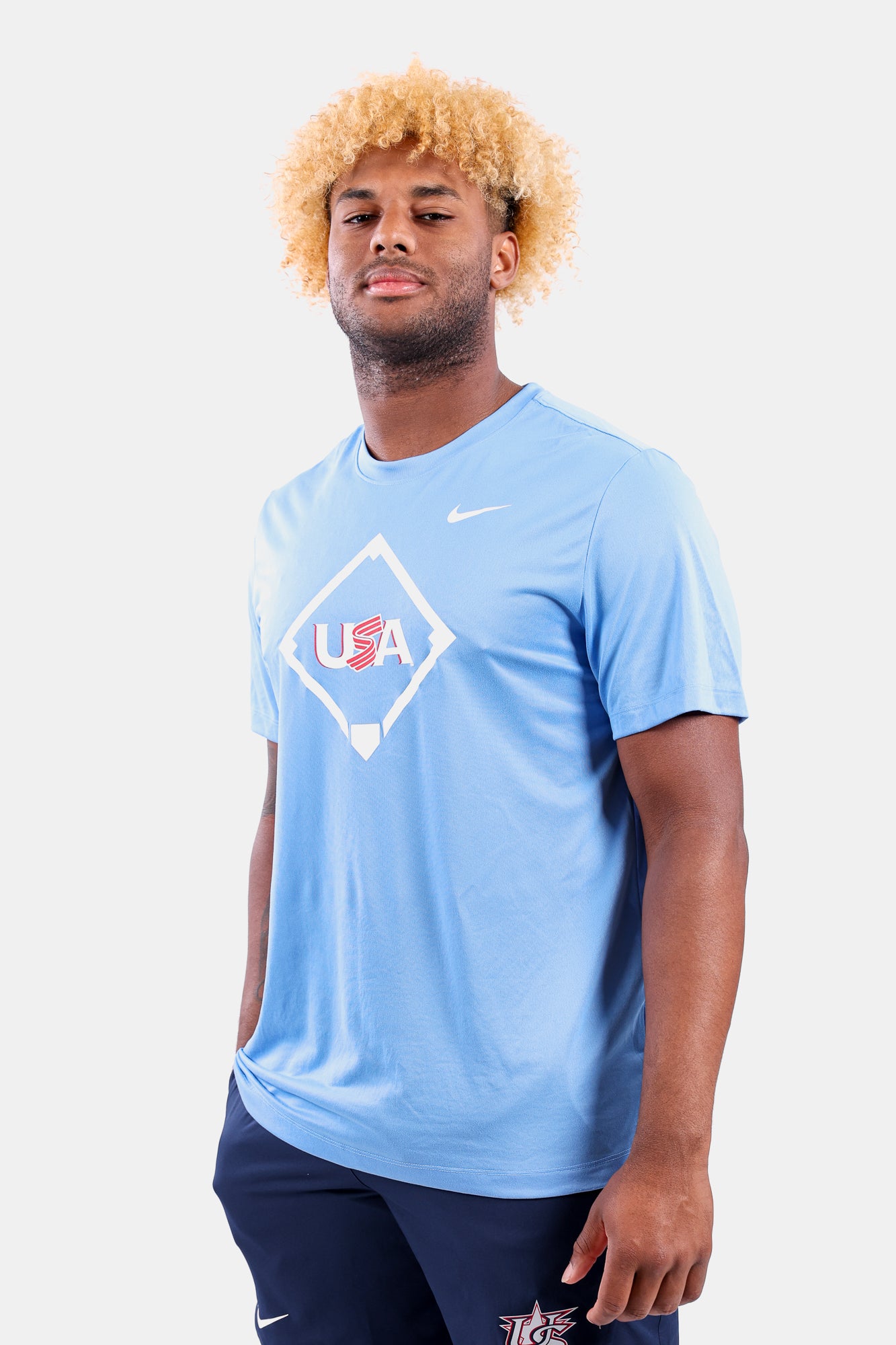 Male model wearing the Light Blue Home Plate Legend Tee featuring the USA Baseball Jersey logo