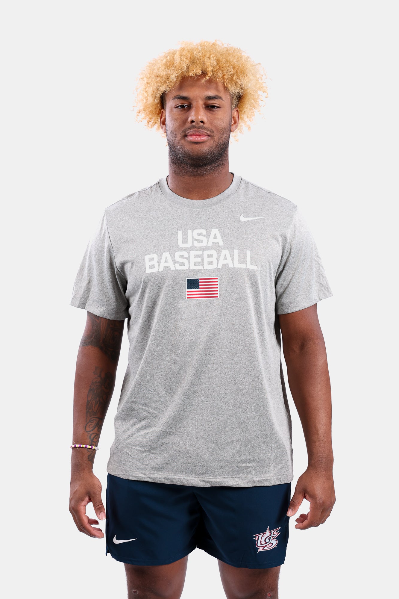 Male model wearing the Heather Grey Dynamic Legend Tee featuring the screen-printed American flag logo