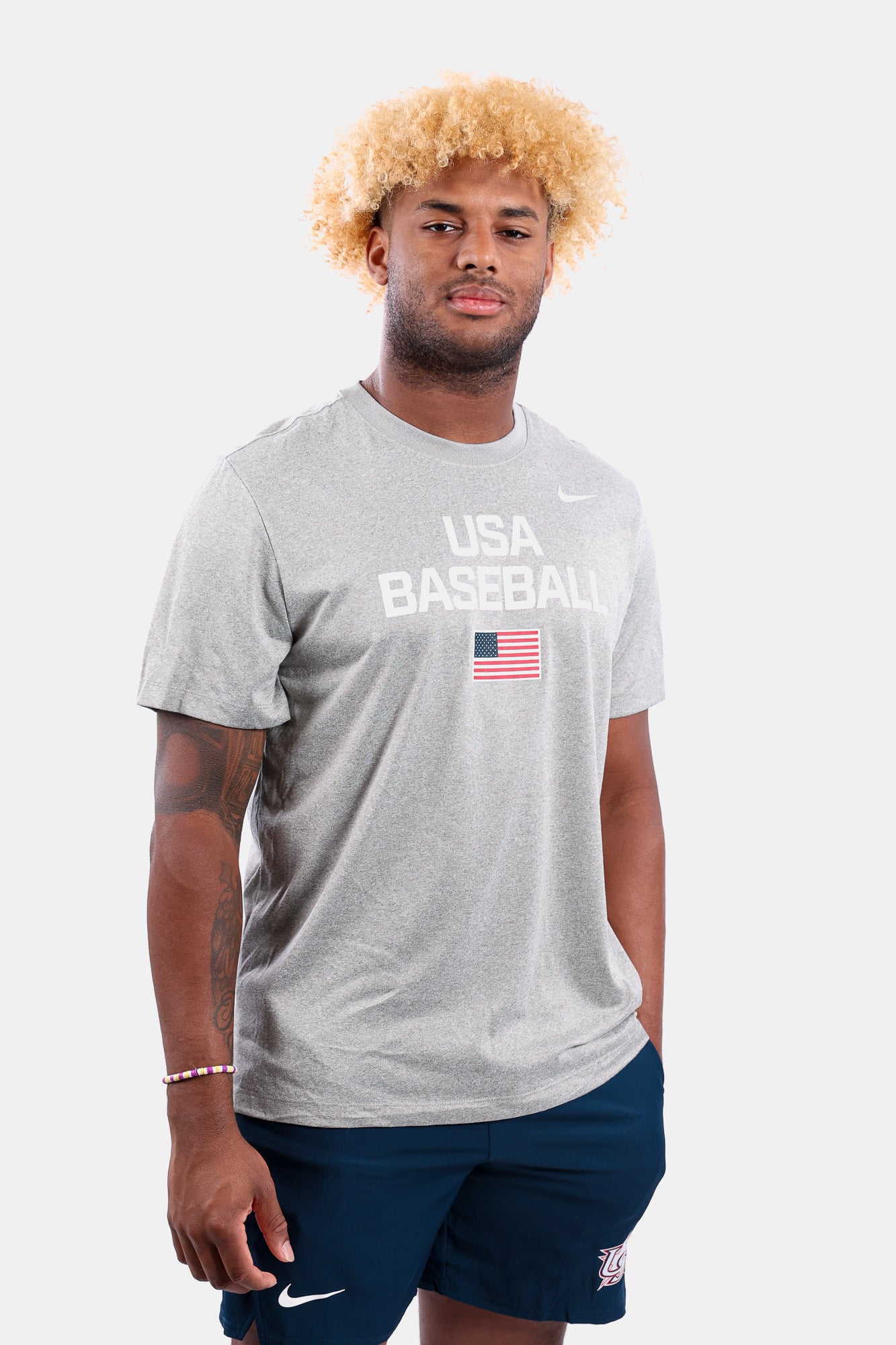 Male model wearing the Heather Grey Dynamic Legend Tee featuring the screen-printed American flag logo