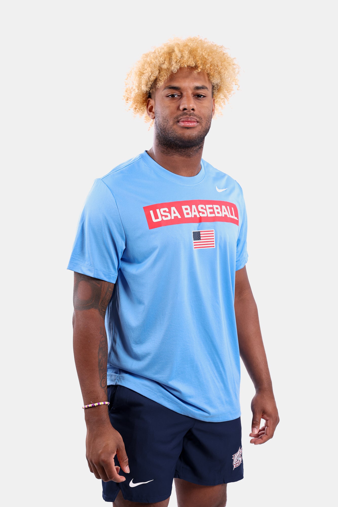 Male model wearing the Light Blue Defined Legend Tee featuring screen-printed American flag logo
