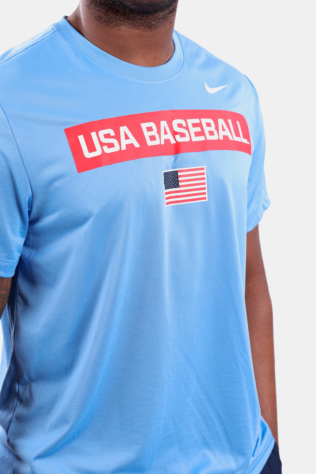 Detail shot of male model wearing the Light Blue Defined Legend Tee featuring screen-printed American flag logo