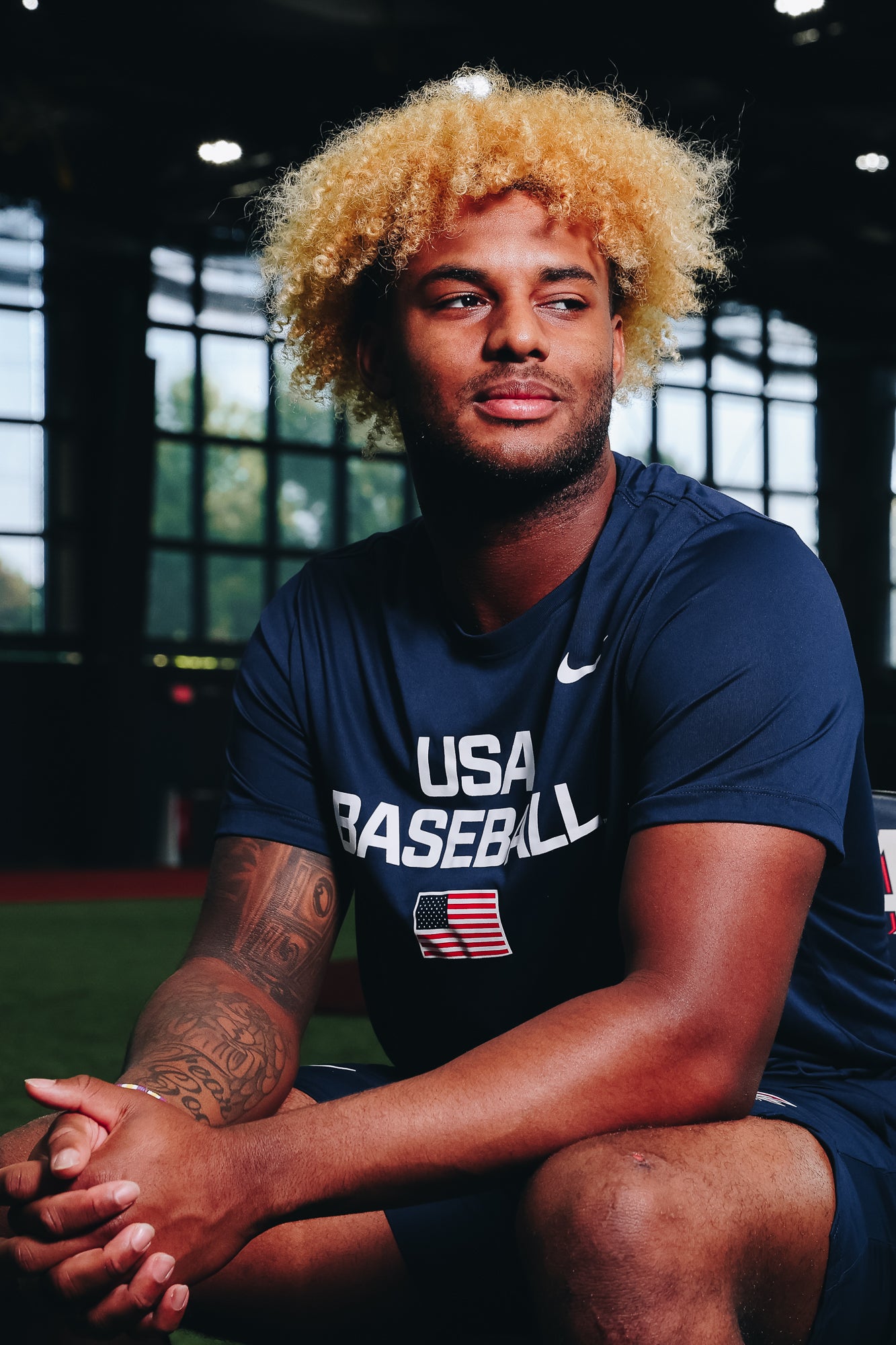 Male model wearing the Navy Dynamic Legend Tee featuring the screen-printed American flag logo in Indoor Training Facility