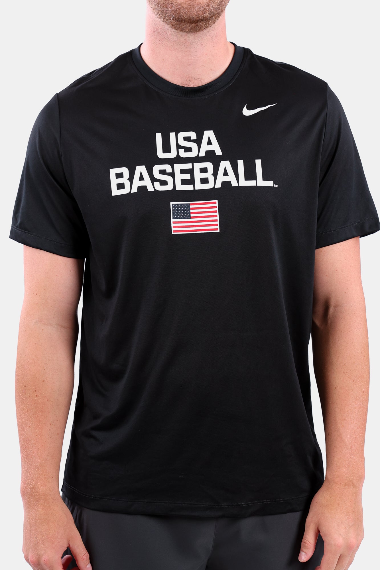 Detail shot of male model wearing the Black Dynamic Legend Tee featuring a screen-printed American flag logo