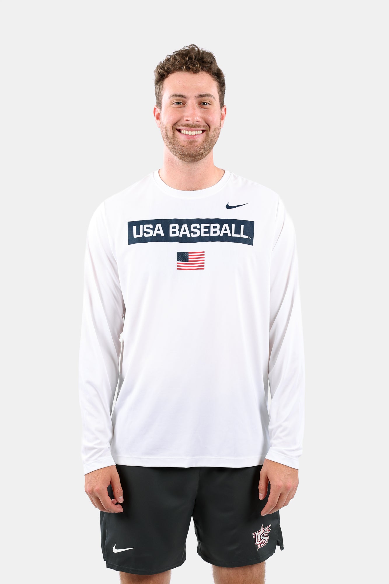 Male model wearing the White Defined Long Sleeve Legend Tee featuring the screen-printed American flag logo