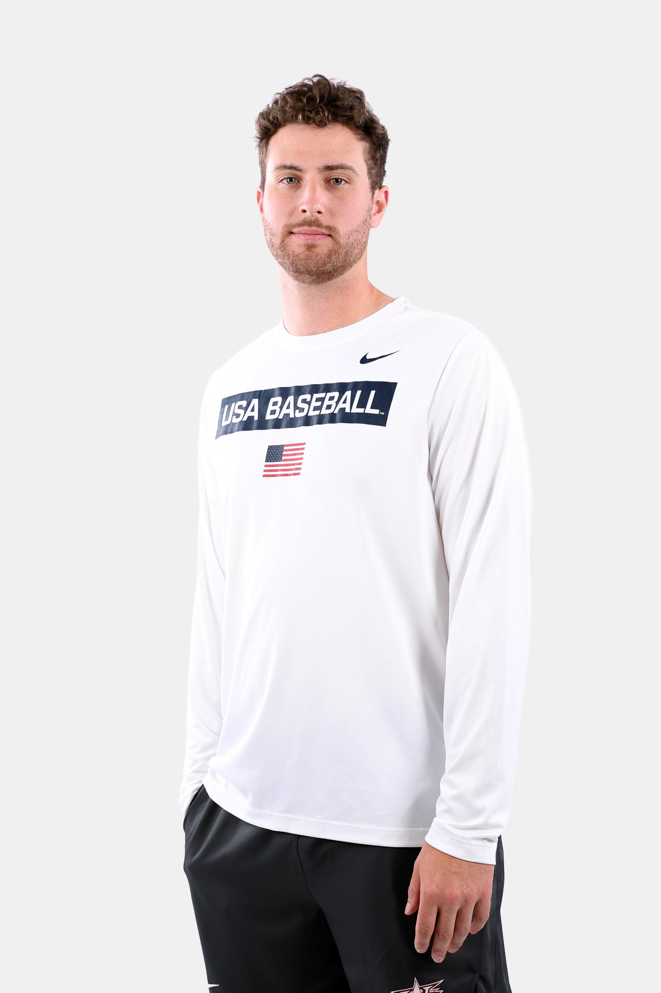 Male model wearing the White Defined Long Sleeve Legend Tee featuring the screen-printed American flag logo