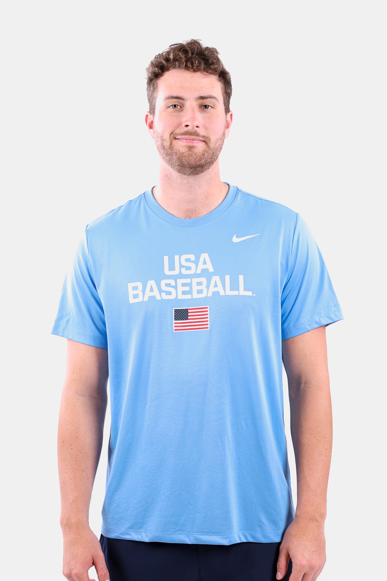 Male model wearing the Light Blue Dynamic Legend Tee featuring the screen-printed American flag logo