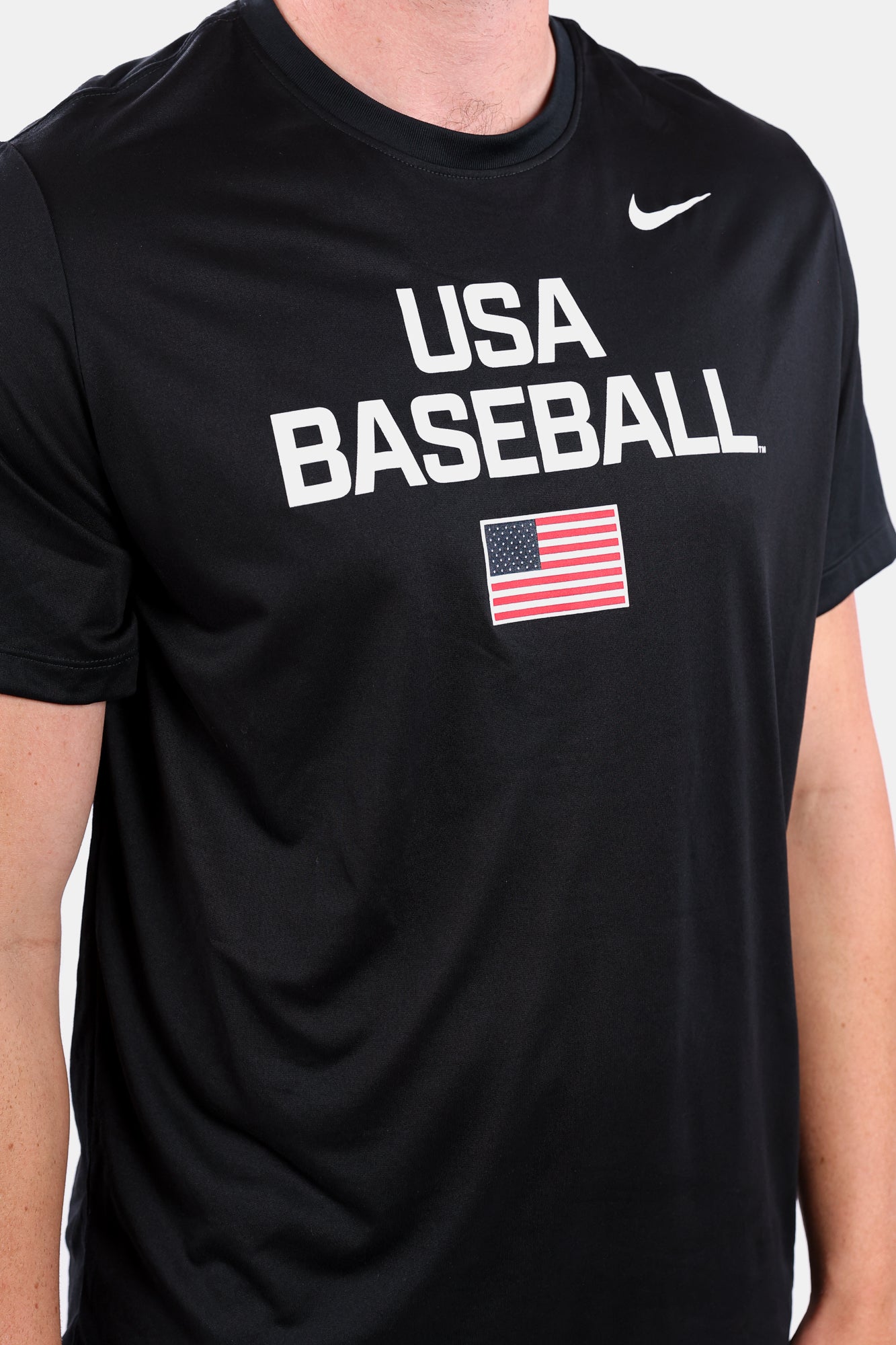 Detail shot of male model wearing the Black Dynamic Legend Tee featuring a screen-printed American flag logo